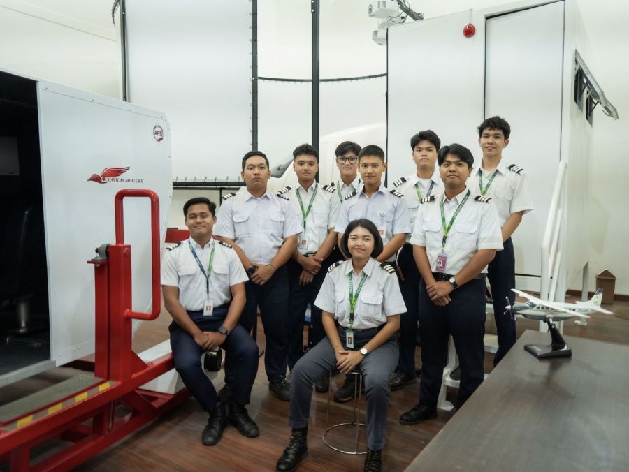 A Smart Flying School student intake in uniform beside the flight simulator